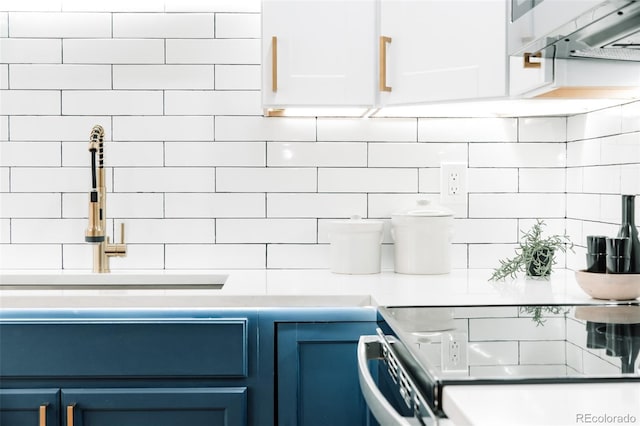 kitchen with blue cabinets, light countertops, white cabinets, and decorative backsplash