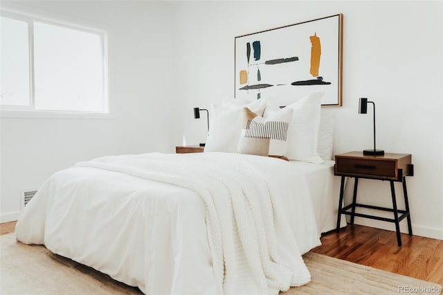 bedroom featuring wood finished floors, visible vents, and baseboards