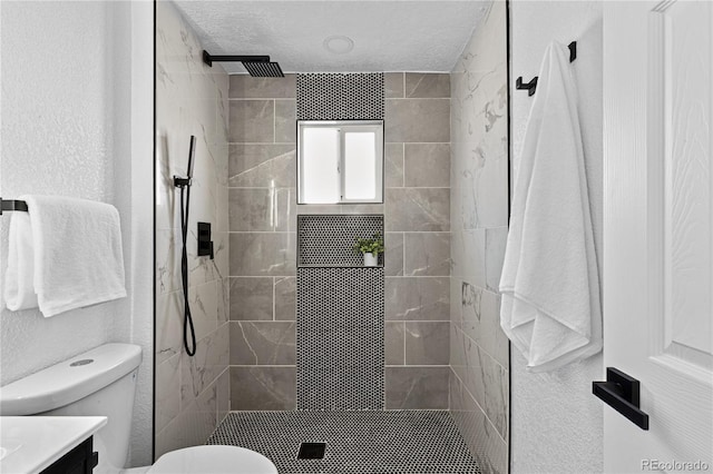 bathroom with a stall shower, vanity, toilet, and a textured ceiling