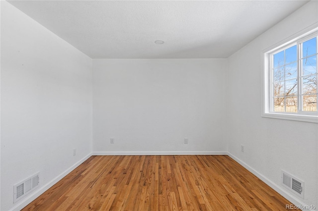 spare room with visible vents, baseboards, and light wood finished floors