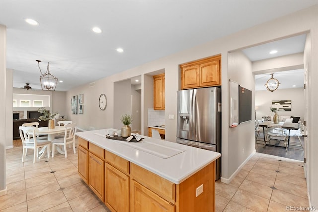 kitchen featuring light tile patterned floors, a center island, pendant lighting, and stainless steel refrigerator with ice dispenser