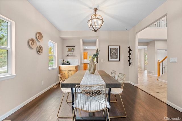 dining area featuring a chandelier, a healthy amount of sunlight, and dark hardwood / wood-style flooring