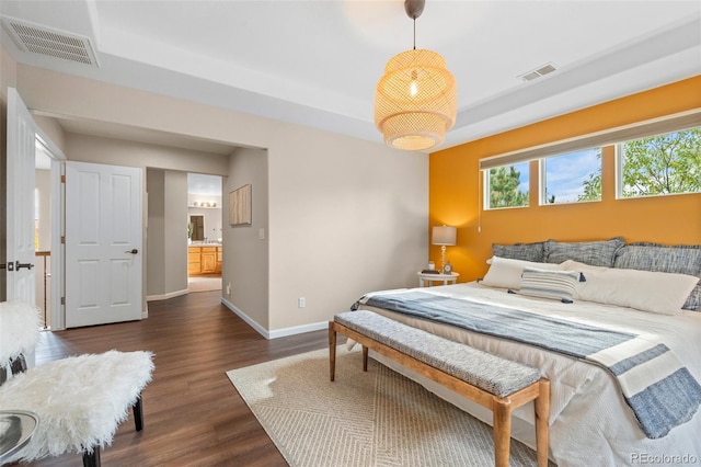 bedroom featuring ensuite bathroom and dark hardwood / wood-style flooring