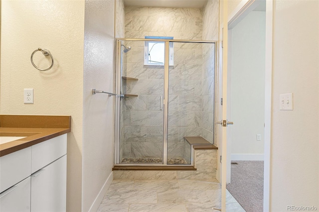 full bath with marble finish floor, a shower stall, baseboards, and vanity