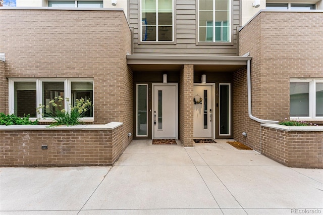 doorway to property with a patio area and brick siding