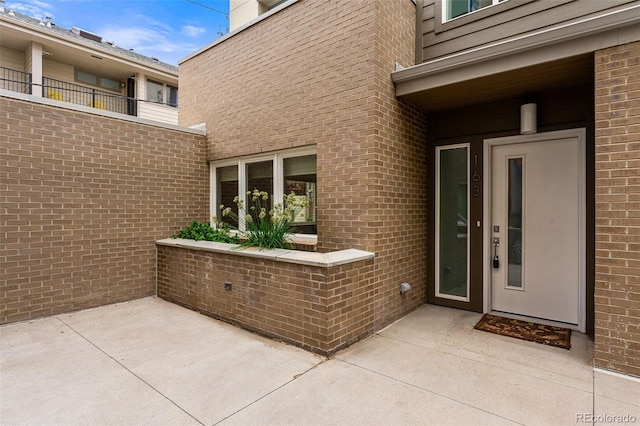 property entrance featuring a patio and brick siding