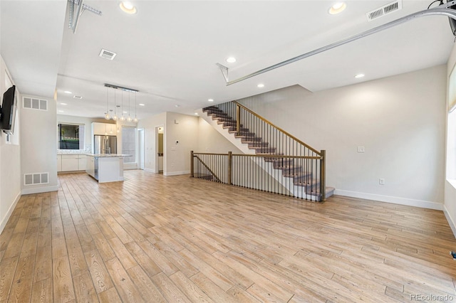 unfurnished living room featuring baseboards, visible vents, and light wood-style floors