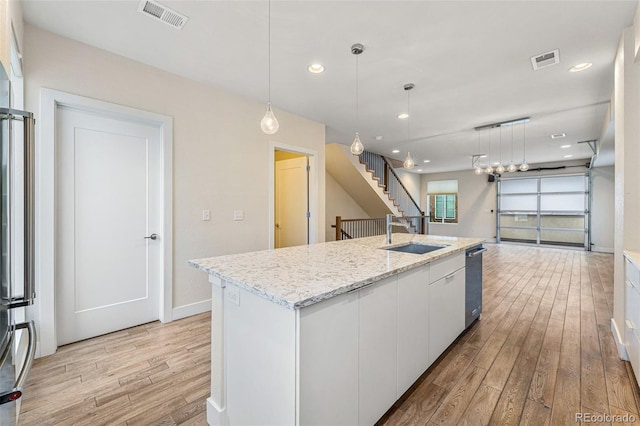 kitchen featuring a kitchen island with sink, a sink, visible vents, white cabinetry, and open floor plan