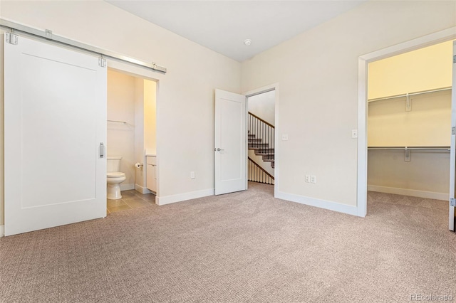 unfurnished bedroom featuring carpet flooring, a closet, baseboards, and a walk in closet