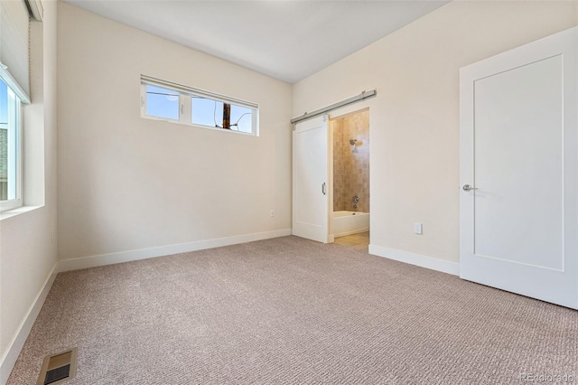 unfurnished bedroom featuring baseboards, ensuite bath, visible vents, and carpet floors