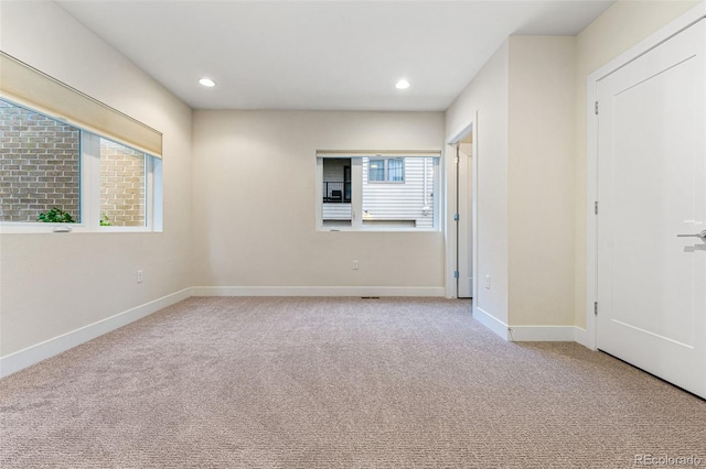 empty room featuring baseboards, recessed lighting, and light colored carpet