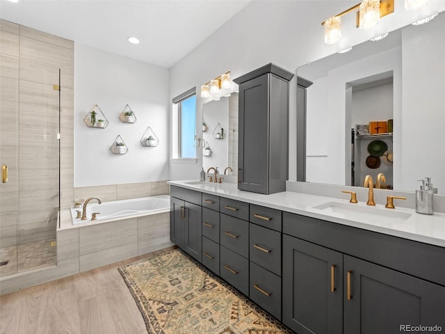 full bath with a garden tub, double vanity, a stall shower, and a sink