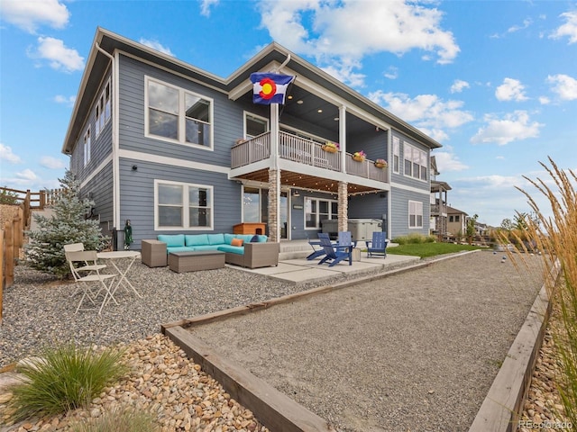 rear view of house with a balcony, a patio area, fence, and an outdoor living space