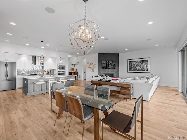 dining room featuring recessed lighting, light wood finished floors, and an inviting chandelier