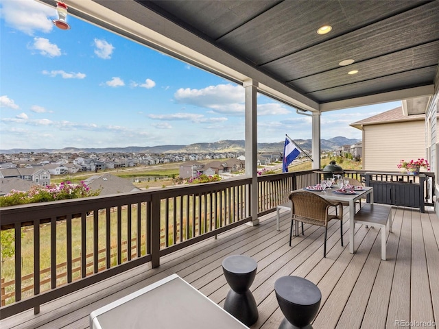 deck featuring outdoor dining space, a mountain view, and a residential view