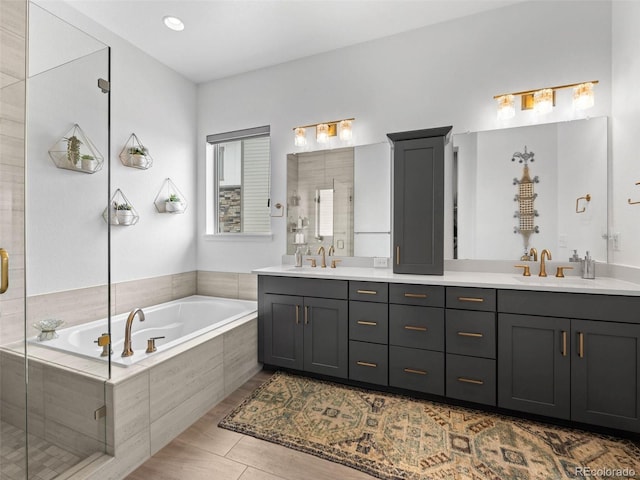 bathroom featuring a stall shower, a sink, a bath, and double vanity