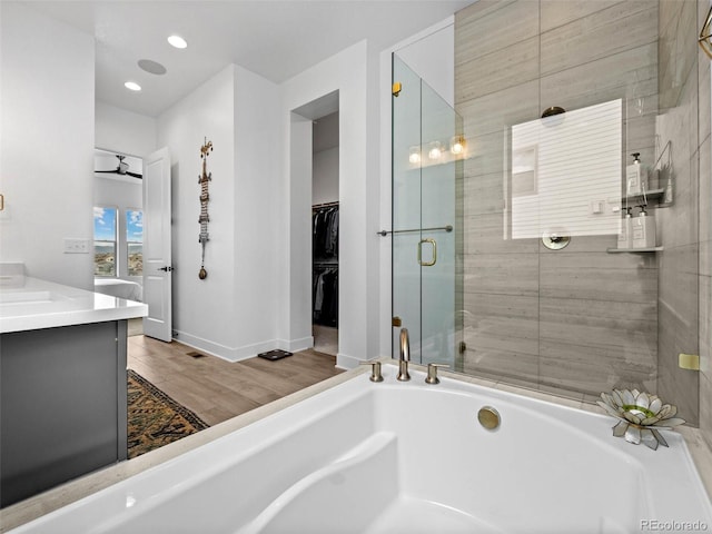 bathroom featuring a washtub, vanity, baseboards, a spacious closet, and a stall shower