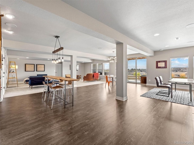 dining area featuring a textured ceiling, dark wood-style flooring, a notable chandelier, and baseboards