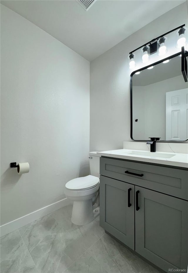 bathroom with baseboards, toilet, marble finish floor, and vanity