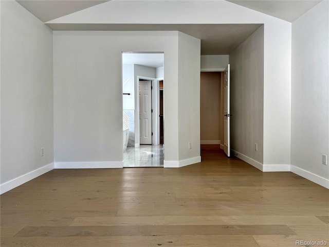 unfurnished room with baseboards, lofted ceiling, and light wood-style floors