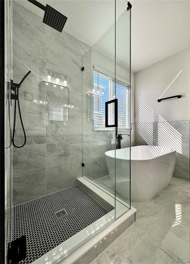 bathroom with a freestanding bath, marble finish floor, a stall shower, and a textured ceiling