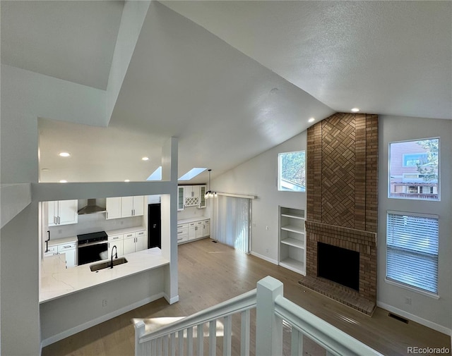 unfurnished living room featuring built in shelves, baseboards, a fireplace, light wood-style floors, and a sink