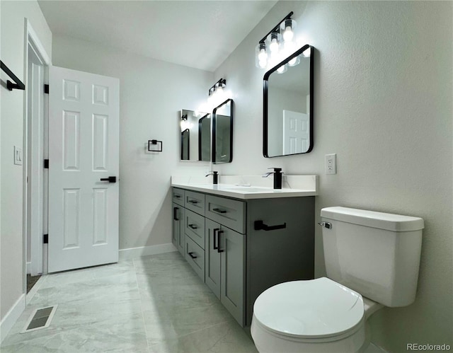 bathroom featuring visible vents, double vanity, a sink, toilet, and marble finish floor