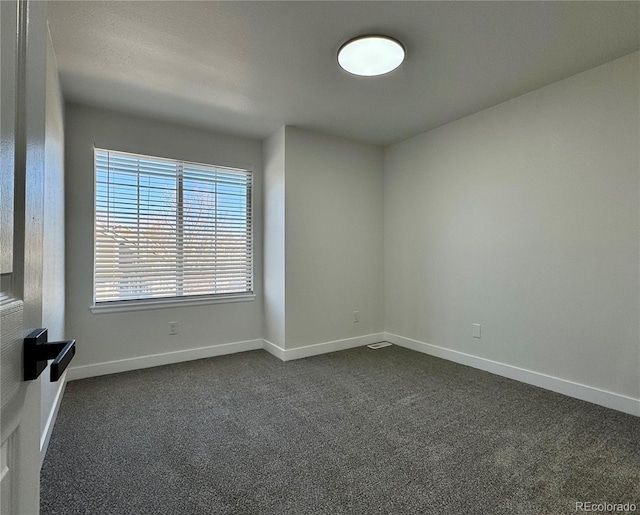 unfurnished room with dark carpet and baseboards