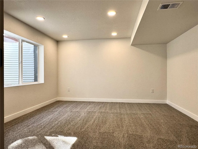 below grade area with visible vents, recessed lighting, baseboards, and dark colored carpet