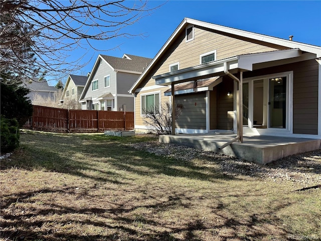 rear view of house with a patio area, a yard, and fence