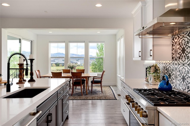 kitchen featuring sink, white cabinetry, plenty of natural light, and wall chimney range hood