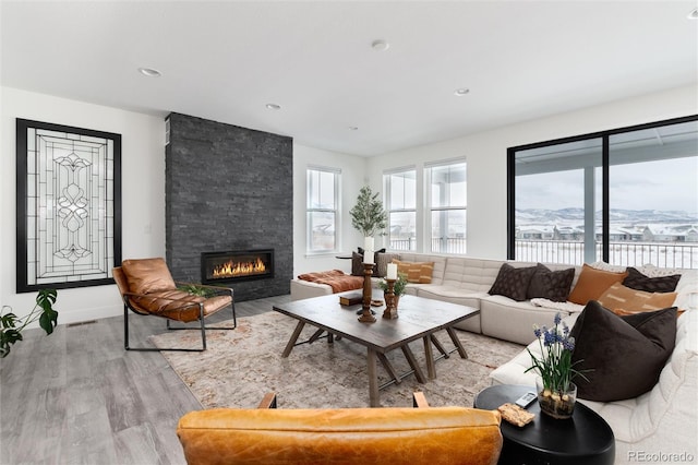 living room featuring a mountain view, light hardwood / wood-style floors, and a stone fireplace