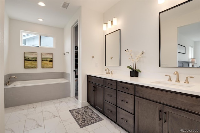 bathroom with tiled bath and vanity