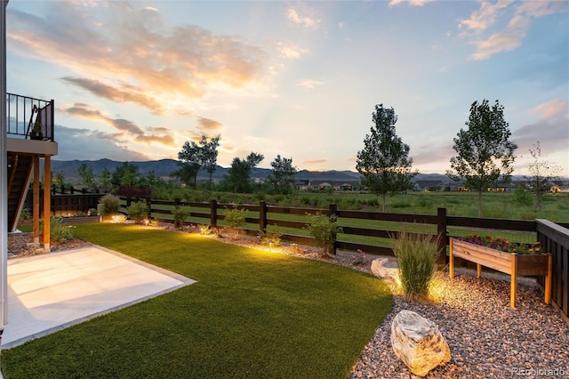 yard at dusk featuring a mountain view and a patio