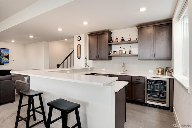 bar featuring dark brown cabinets, beverage cooler, and sink