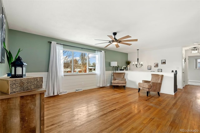 sitting room featuring ceiling fan with notable chandelier and light hardwood / wood-style flooring