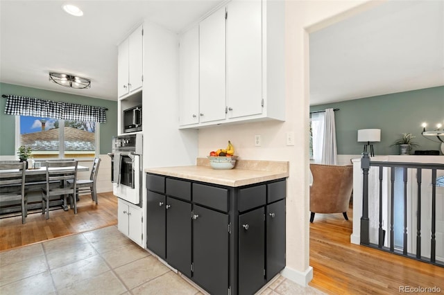 kitchen with appliances with stainless steel finishes, white cabinets, and light wood-type flooring