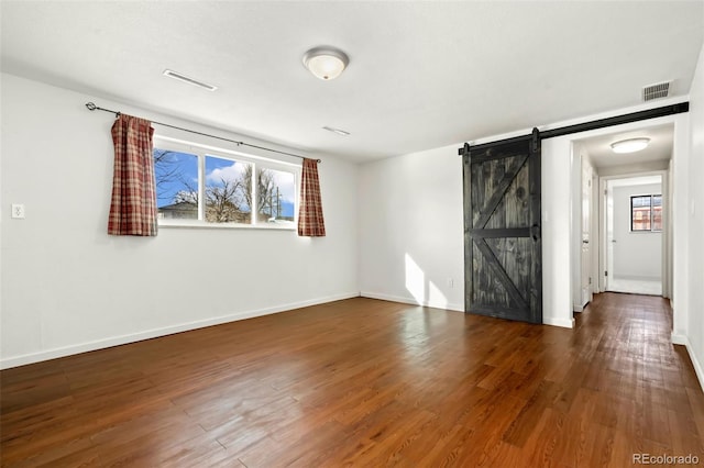 spare room with dark hardwood / wood-style floors and a barn door