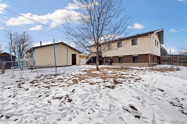 snow covered rear of property featuring a trampoline