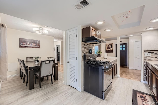 kitchen featuring tasteful backsplash, stainless steel range with gas cooktop, dark brown cabinetry, and light hardwood / wood-style floors