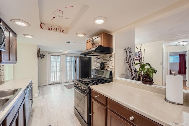 kitchen with sink, appliances with stainless steel finishes, backsplash, a raised ceiling, and french doors