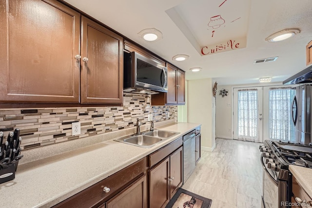 kitchen with stainless steel appliances, sink, french doors, and decorative backsplash