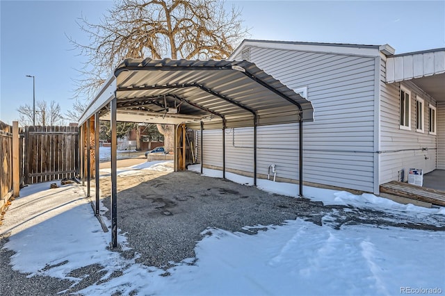 snow covered parking area with a carport