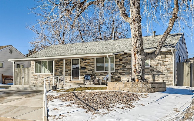 view of front of house featuring covered porch, stone siding, and a shingled roof