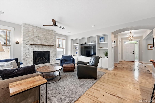 8276 E 28th Dr, Denver, CO 80238 - living room with arched walkways, a ceiling fan, light wood-style floors, a stone fireplace, and baseboards