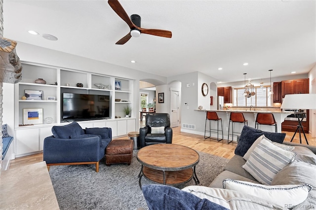 8276 E 28th Dr, Denver, CO 80238 - living room with arched walkways, ceiling fan, light wood-style floors, recessed lighting, and built in shelves