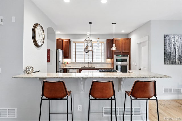 8276 E 28th Dr, Denver, CO 80238 - kitchen with stainless steel appliances, a sink, a kitchen breakfast bar, light wood-style flooring, and recessed lighting