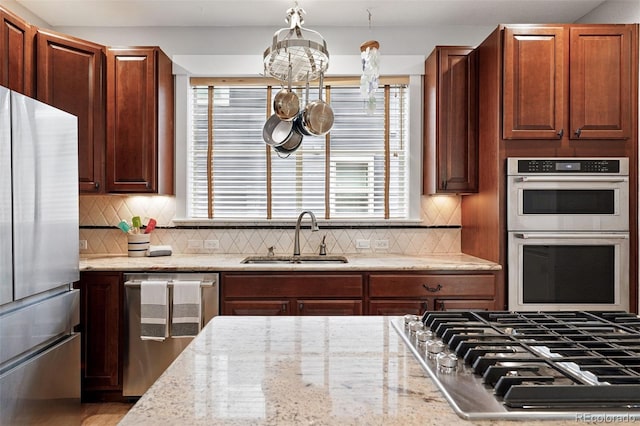 8276 E 28th Dr, Denver, CO 80238 - kitchen featuring appliances with stainless steel finishes, a sink, light stone counters, and decorative backsplash