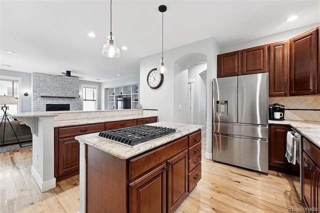 8276 E 28th Dr, Denver, CO 80238 - kitchen featuring appliances with stainless steel finishes, a kitchen island, light wood-type flooring, arched walkways, and open floor plan