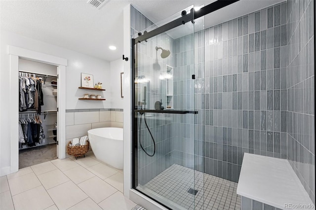 8276 E 28th Dr, Denver, CO 80238 - bathroom featuring tile patterned flooring, a freestanding bath, tile walls, a walk in closet, and a stall shower